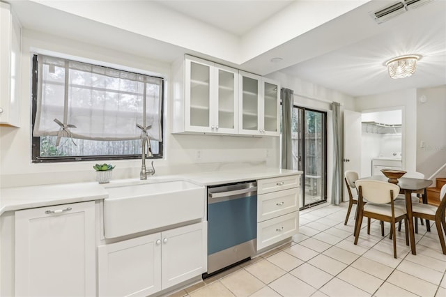 kitchen featuring sink, light tile patterned floors, dishwasher, white cabinets, and washer / dryer