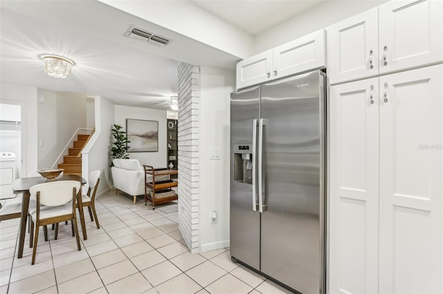 kitchen featuring washer / clothes dryer, light tile patterned floors, white cabinets, and stainless steel fridge with ice dispenser