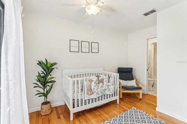 bedroom featuring hardwood / wood-style flooring, a nursery area, and ceiling fan