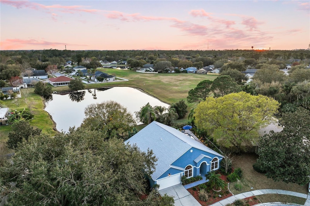 aerial view at dusk featuring a water view