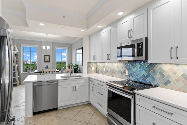 kitchen with sink, white cabinets, ornamental molding, kitchen peninsula, and stainless steel appliances