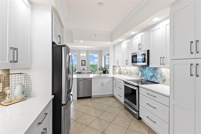 kitchen with a raised ceiling, white cabinetry, stainless steel appliances, crown molding, and light stone countertops