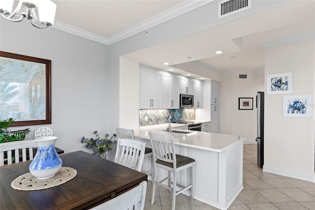 tiled dining room featuring crown molding, a chandelier, and sink