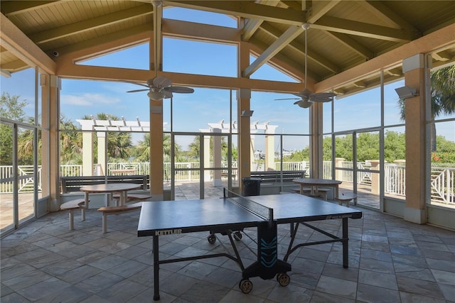 unfurnished sunroom with lofted ceiling with beams, a wealth of natural light, and ceiling fan