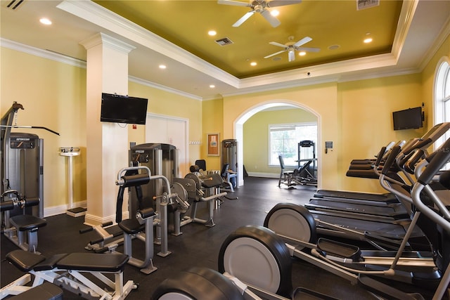 exercise room with ceiling fan, ornamental molding, and a raised ceiling