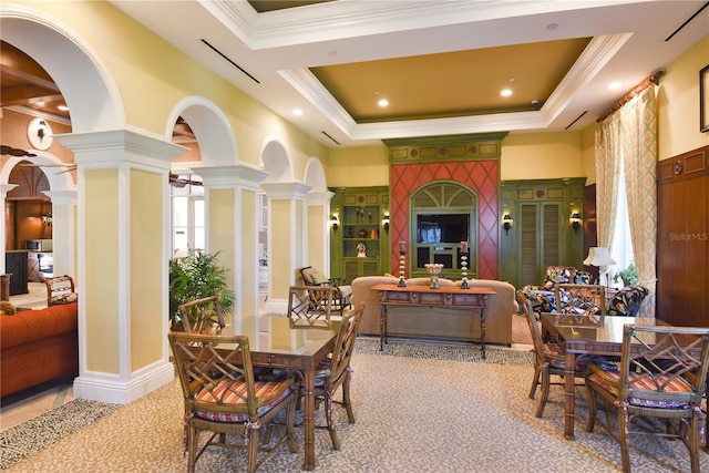 dining space with crown molding, a tray ceiling, and decorative columns