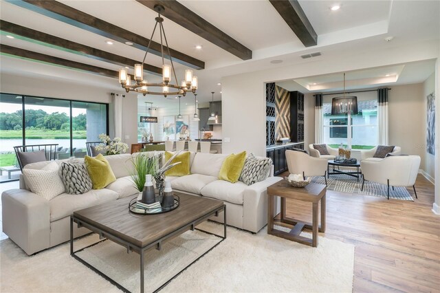 living room featuring beam ceiling, a notable chandelier, and light hardwood / wood-style floors