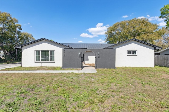 ranch-style home with stucco siding, fence, metal roof, and a front yard