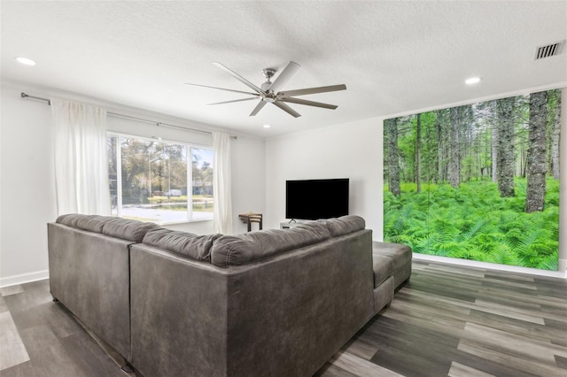 living room featuring a ceiling fan, a textured ceiling, visible vents, and wood finished floors