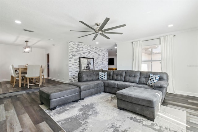 living room featuring ornamental molding, visible vents, baseboards, and wood finished floors