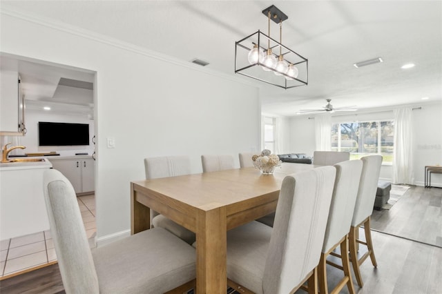 dining room with light wood finished floors, visible vents, a ceiling fan, crown molding, and recessed lighting