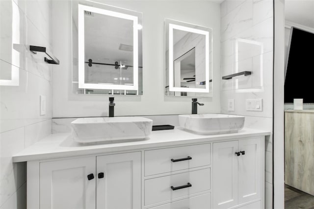 full bathroom featuring a sink, tile walls, and double vanity