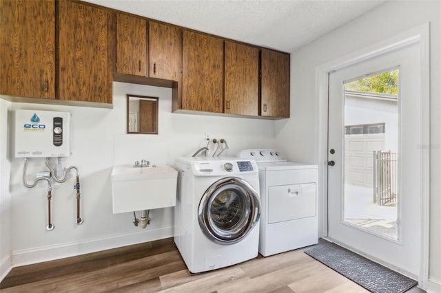 laundry room with cabinet space, wood finished floors, washing machine and clothes dryer, tankless water heater, and a textured ceiling