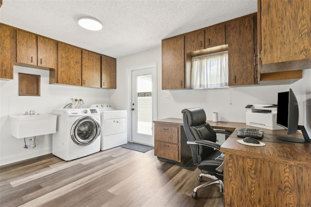 interior space featuring a textured ceiling, a sink, wood finished floors, independent washer and dryer, and cabinet space