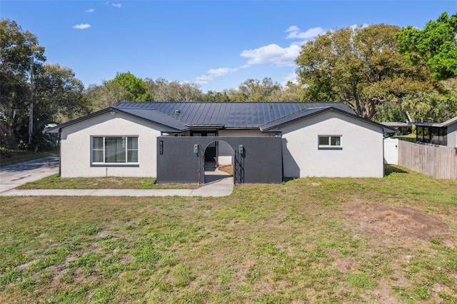 back of house featuring a yard, stucco siding, a standing seam roof, fence, and metal roof