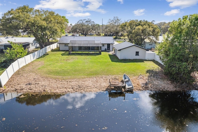 back of house with a lawn, a water view, a fenced backyard, and a lanai