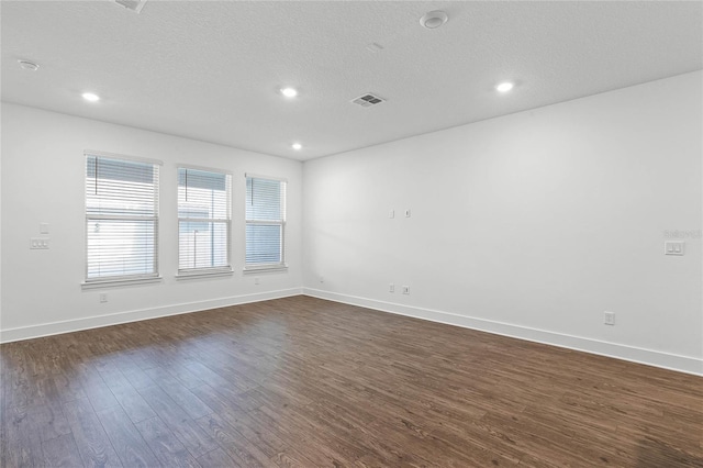 spare room featuring dark hardwood / wood-style floors and a textured ceiling