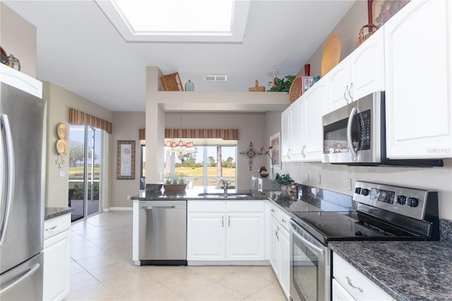 kitchen featuring dark stone countertops, stainless steel appliances, sink, and white cabinets