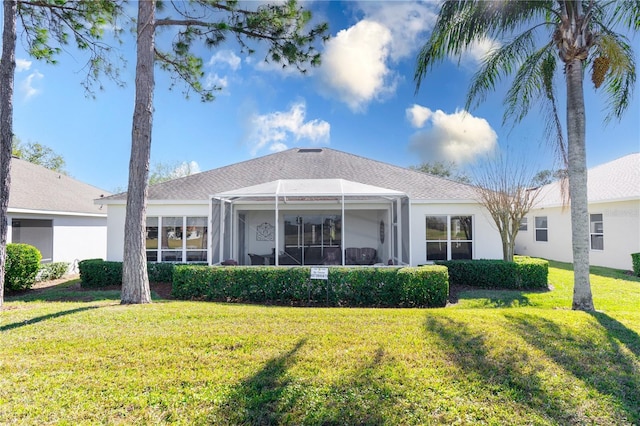 rear view of property with a lanai and a lawn