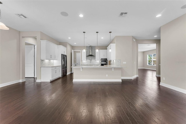 interior space featuring backsplash, hanging light fixtures, white cabinets, dark hardwood / wood-style flooring, and wall chimney exhaust hood