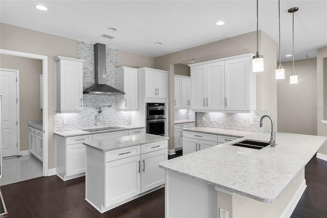 kitchen with wall chimney exhaust hood, sink, white cabinetry, a kitchen island, and pendant lighting