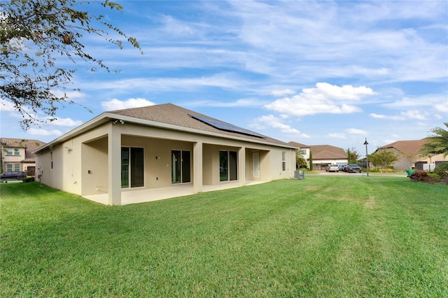 rear view of house with central AC, a lawn, solar panels, and a patio area