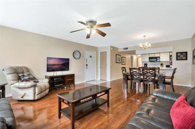 living room featuring wood-type flooring and ceiling fan with notable chandelier