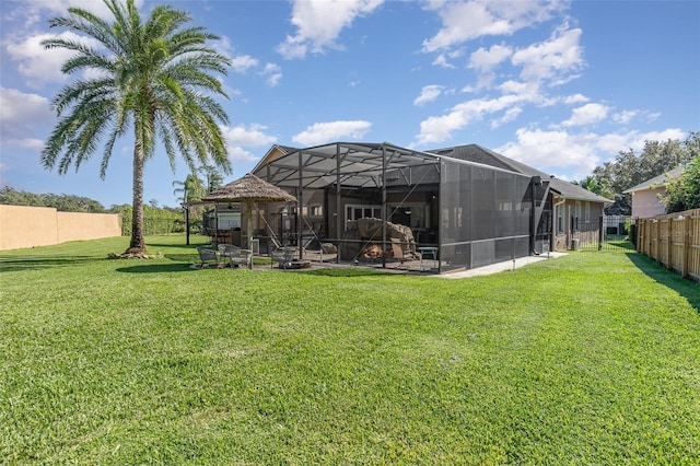 rear view of property featuring a yard, glass enclosure, and a patio area