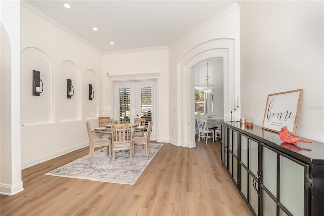 dining space featuring french doors, ornamental molding, and light hardwood / wood-style flooring