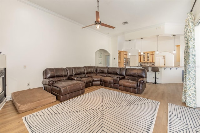 living room featuring crown molding, ceiling fan, and light wood-type flooring