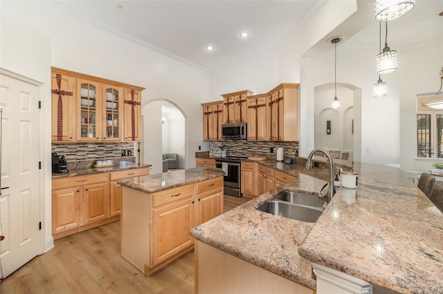 kitchen featuring appliances with stainless steel finishes, sink, light stone counters, and decorative light fixtures