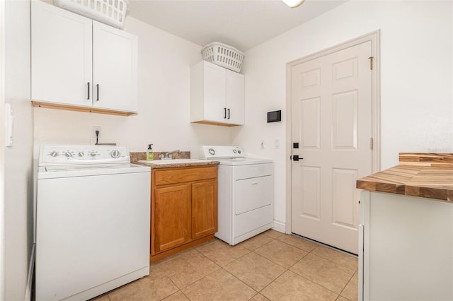 laundry area featuring cabinets, sink, light tile patterned floors, and independent washer and dryer