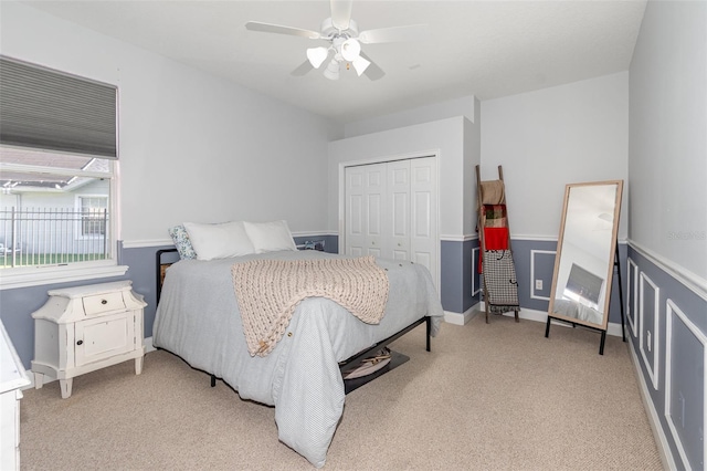 bedroom featuring light colored carpet, ceiling fan, and a closet