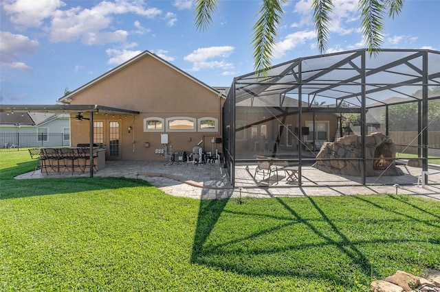 rear view of house featuring ceiling fan, glass enclosure, a patio area, and a lawn