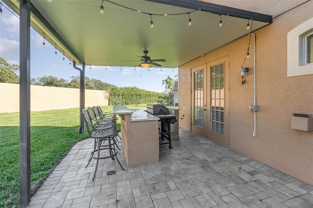 view of patio featuring a bar, french doors, ceiling fan, and exterior kitchen