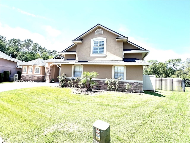 view of front facade featuring stone siding, a front lawn, stucco siding, and fence