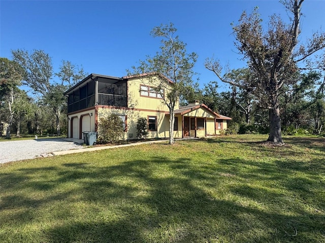 view of front of house featuring a front lawn, a garage, and a sunroom