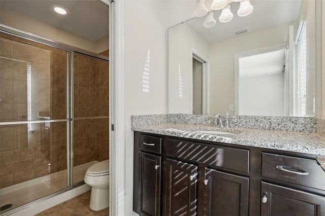 bathroom featuring tile patterned flooring, vanity, a shower with shower door, and toilet