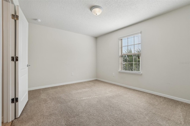 carpeted empty room featuring a textured ceiling