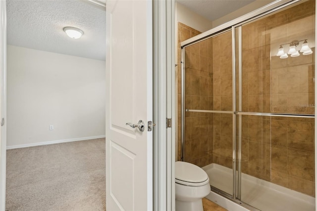 bathroom featuring a textured ceiling, a shower with door, and toilet