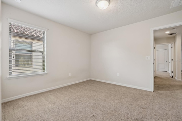 empty room with light colored carpet and a textured ceiling