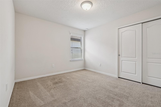 unfurnished bedroom with light colored carpet, a closet, and a textured ceiling