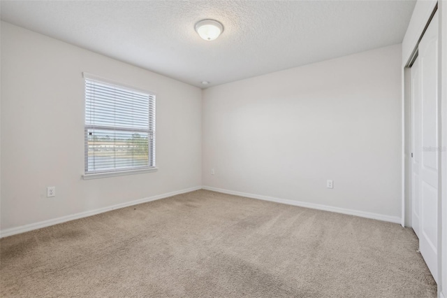 carpeted empty room featuring a textured ceiling