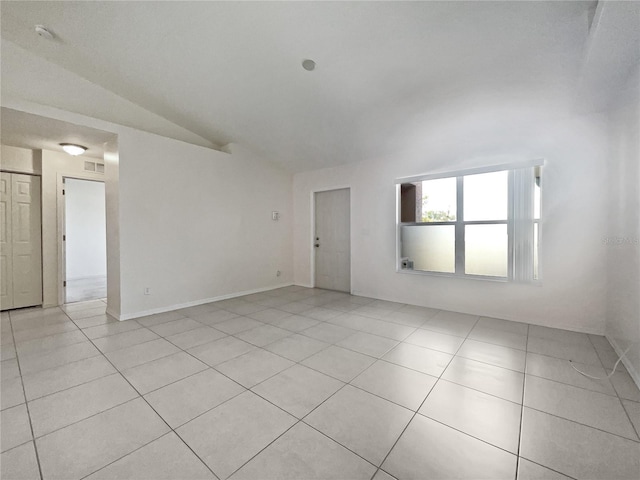 spare room featuring light tile patterned flooring and vaulted ceiling