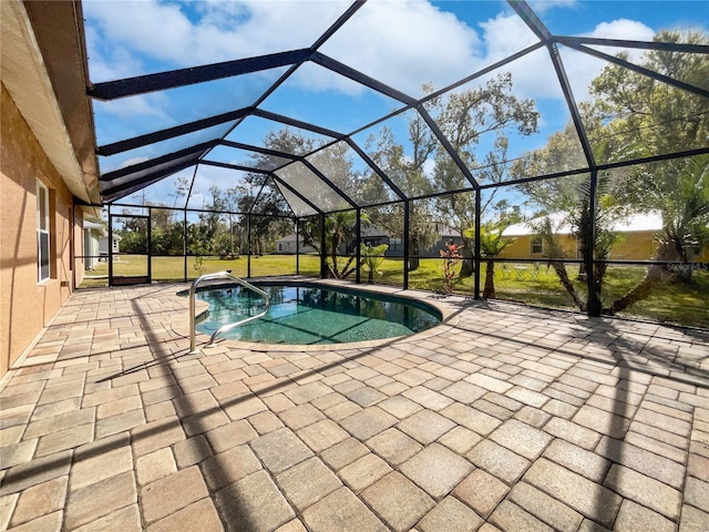 view of pool with a patio, glass enclosure, and a lawn