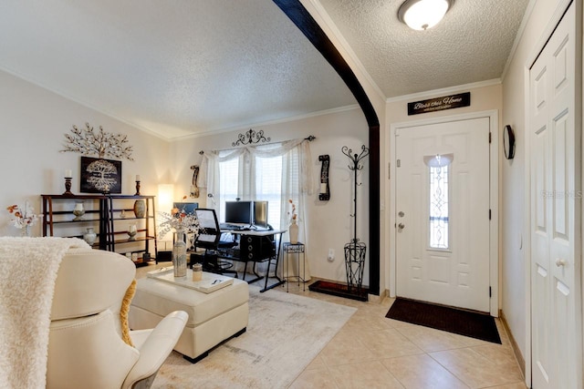 foyer entrance with ornamental molding, a textured ceiling, and light tile patterned floors