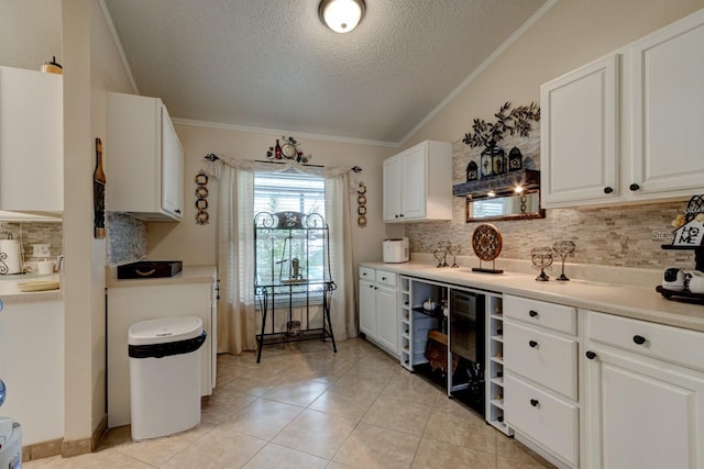 kitchen with white cabinetry, backsplash, light tile patterned floors, crown molding, and a textured ceiling