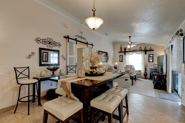 tiled dining area featuring lofted ceiling, crown molding, a barn door, and a textured ceiling