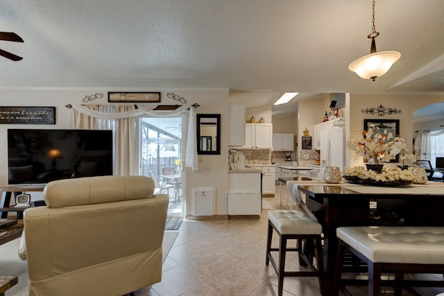 tiled dining space with a wealth of natural light, ornamental molding, and a textured ceiling