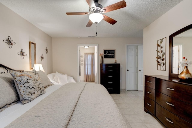 bedroom with light tile patterned flooring, ceiling fan, and a textured ceiling